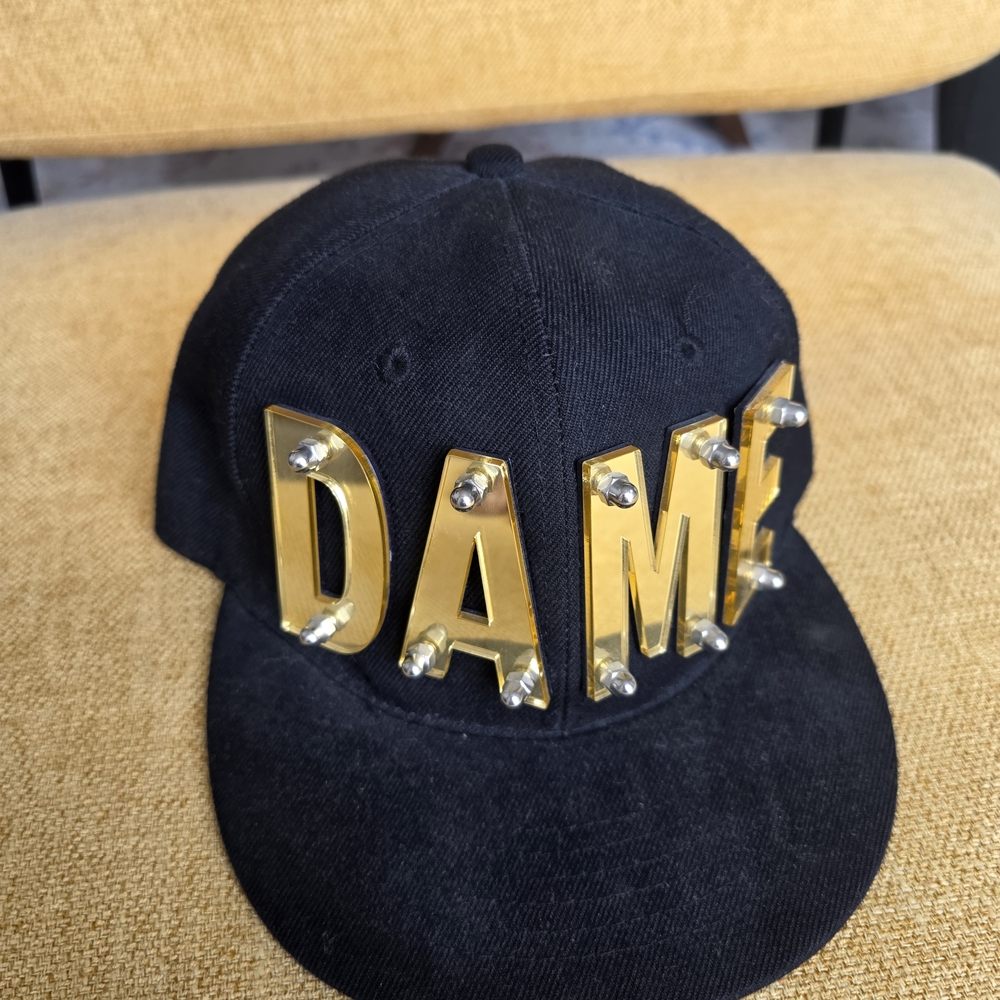 Black Snapback Hat with Gold 'DAME' Lettering
